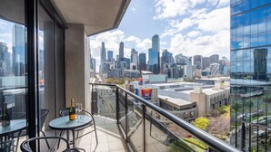 Un balcon avec vue sur la ville, une table avec des chaises et une bouteille de champagne.