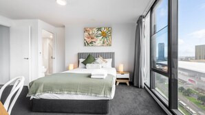 Une chambre d’hôtel moderne avec un grand lit, une vue sur la ville et un tableau au mur.