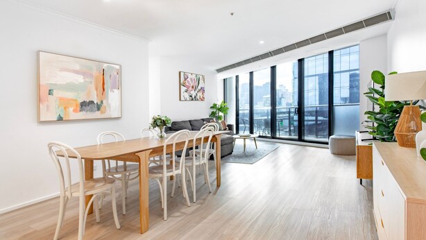 Un salon moderne avec un coin repas, de grandes fenêtres et une vue sur la ville.