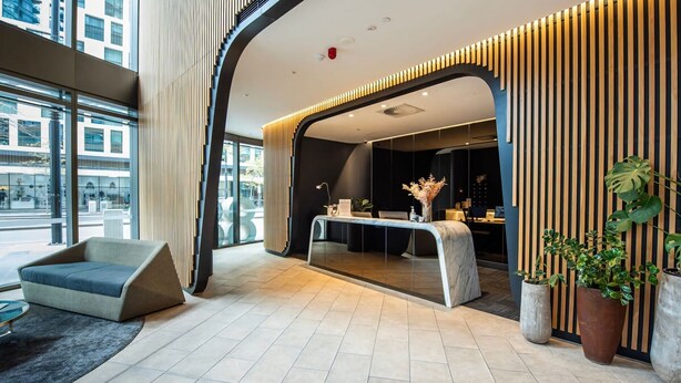 A modern reception area with a curved desk, seating, and large windows.