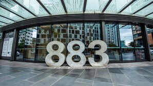 A modern building with a glass facade and a large '883' sculpture in front.