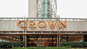 En hotelindgang med et stort 'CROWN'-skilt, moderne design og en central dekorativ konstruktion.