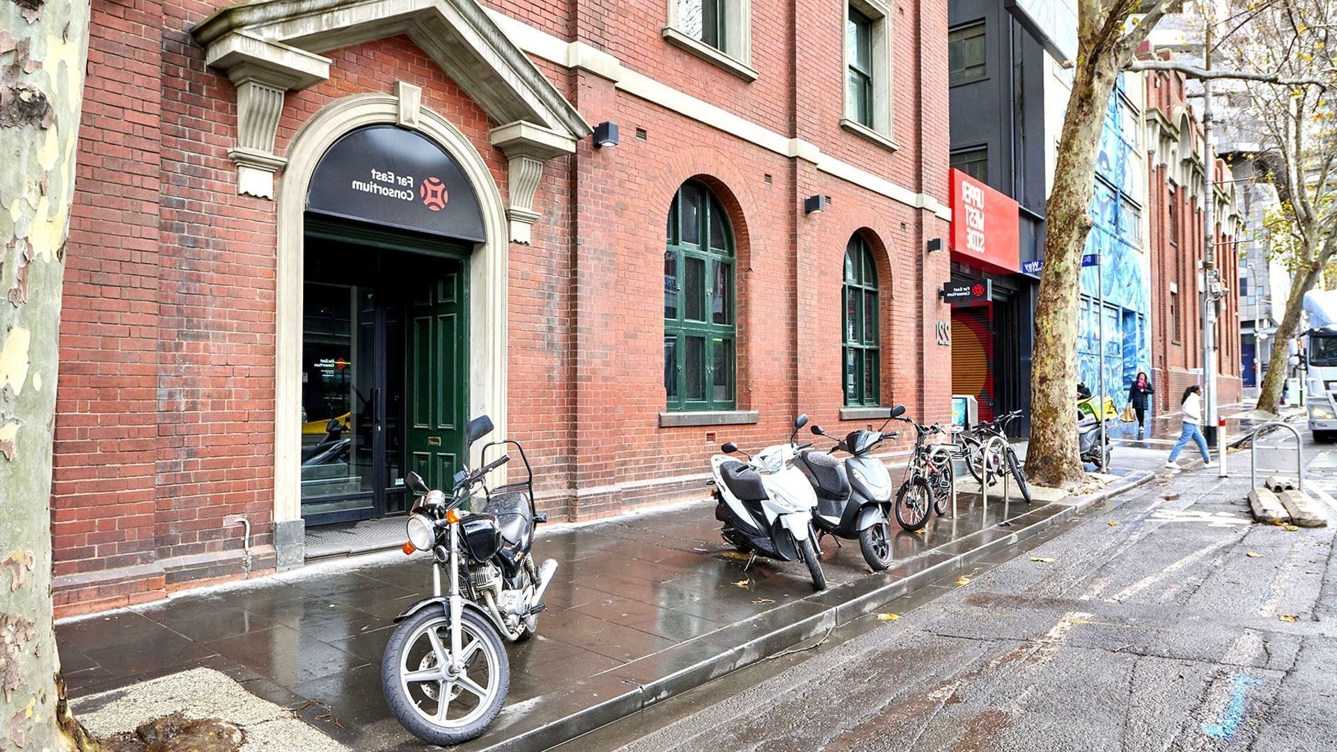 A brick building with a storefront and a row of parked scooters.