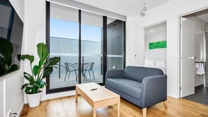 A modern living room with a grey sofa, a wooden coffee table, and a potted plant.