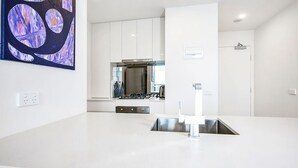 A modern kitchen with white cabinetry, a stainless steel sink, and a gas stove.