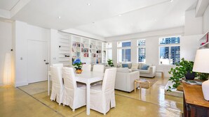 Un amplio salón con una mesa de comedor, sillas, un sofá y una estantería.