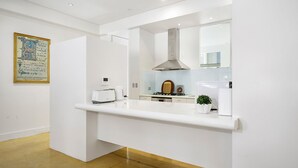 Una cocina moderna con una encimera blanca, una estufa y una pequeña planta en maceta.