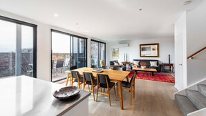 A modern living space with a dining area, a sofa set, and a staircase. - Sweet Escape - Chocolate Factory (Fitzroy)