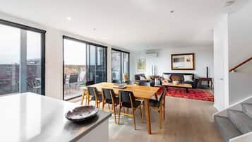 A modern living space with a dining area, a sofa set, and a staircase.