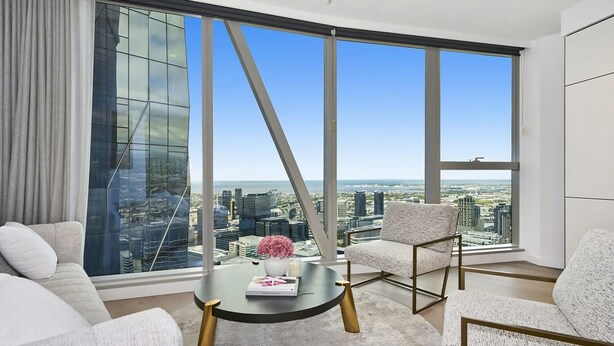 A modern living room with a large city view, a round coffee table, and two armchairs. - Manhattan West Side 57 (Melbourne)
