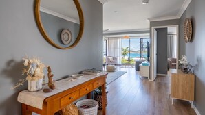 A spacious living room with a wooden coffee table, a large mirror, and a view of the ocean through large windows. - Spectacular Ocean View Home in Bombo (Bombo)