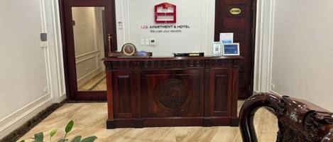 A reception desk with a sign reading "LEE APARTMENT & HOTEL We care your dreams" in a hotel lobby.