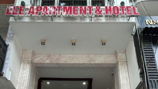 The entrance of Lee Apartment & Hotel with a glass door, a visible staircase, and a potted plant outside. - Lee Apartment & Hotel (Hai Phong)