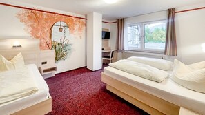 A hotel room with a bed, a desk, a TV, and a window with curtains. - Comfortable and versatile room -perfect for relaxation, work and exchange (Winterberg)