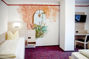 Ein Hotelzimmer mit einem Bett, einem Schreibtisch, einem Sessel, einem Fernseher und einem Wandbild.