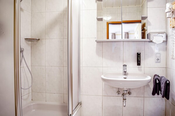 A modern bathroom with a glass-enclosed shower, a white sink, and a mirror above it.