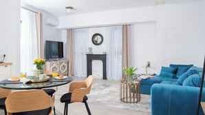 Ein modernes Wohnzimmer mit einem blauen Sofa, einem Essbereich mit einem Glastisch und einem Kamin.