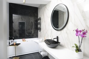 Une salle de bain moderne avec un lavabo noir, un plan de toilette blanc et un grand miroir.