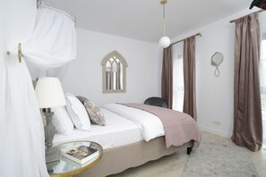A bedroom with a bed, bedside table, lamp, and a window with curtains. - The Clock (Voluntari)