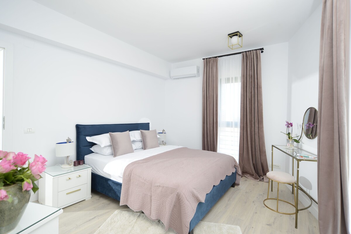 Un dormitorio moderno con cama, mesita de noche y un escritorio pequeño con silla.