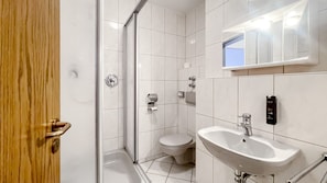 A modern bathroom with a glass shower enclosure, a white toilet, and a white sink with a mirror above it. - Comfortable and versatile room -perfect for relaxation, work and exchange (Winterberg)
