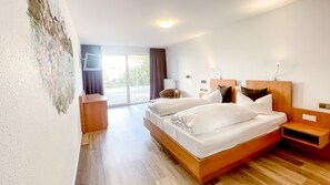 A hotel room with a large bed, a desk, a chair, and a view of the outdoors. - Comfortable and versatile room -perfect for relaxation, work and exchange (Winterberg)