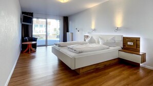 A modern hotel room with a bed, bedside tables, a TV, and a view of the outside. - Comfortable and versatile room -perfect for relaxation, work and exchange (Winterberg)