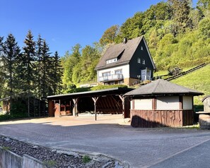 A two-story house with a covered porch and a small wooden structure. - Comfortable and versatile room -perfect for relaxation, work and exchange (Winterberg)