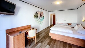 A bedroom with a bed, a desk, a chair, a TV, and a wall painting. - Comfortable and versatile room -perfect for relaxation, work and exchange (Winterberg)