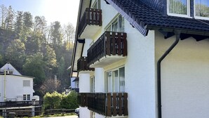 A multi-story building with balconies, a sloped roof, and a pathway leading to a smaller structure. - Comfortable and versatile room -perfect for relaxation, work and exchange (Winterberg)