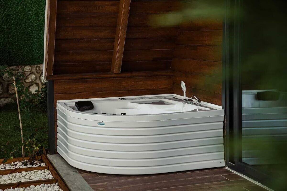 A spa-style hot tub with a wooden backdrop and a glass door.