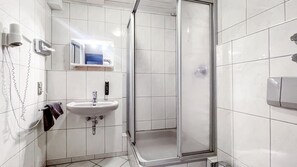A bathroom with a shower, sink, and towel rack. - Comfortable and versatile room -perfect for relaxation, work and exchange (Winterberg)