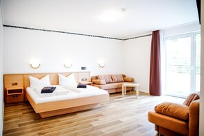A hotel room with a bed, a sofa, a small table, and a chair.