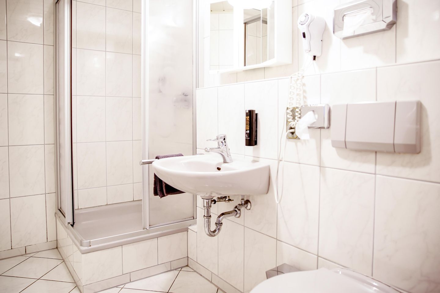 Un bagno moderno con cabina doccia in vetro, lavandino bianco e water.