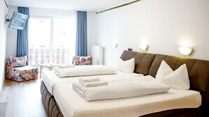 Ett hotellrum med en säng, ett litet bord, en stol och en tv som är monterad på väggen.