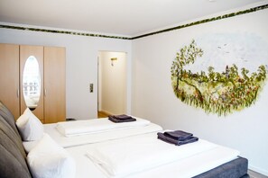 Una habitación de hotel con cama, espejo, armario y un mural en la pared.