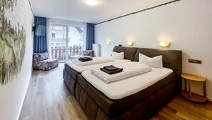 Ett hotellrum med två sängar, en balkong, en TV och ett litet bord.