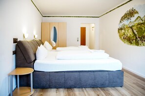 A modern bedroom with a large bed, a small side table, and a painting on the wall. - Comfortable and versatile room -perfect for relaxation, work and exchange (Winterberg)