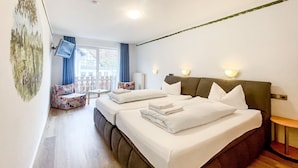 A hotel room with two beds, a television, a window with curtains, and a small table. - Comfortable and versatile room -perfect for relaxation, work and exchange (Winterberg)