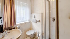 A bathroom with a sink, toilet, and shower. - Comfortable and versatile room -perfect for relaxation, work and exchange (Winterberg)