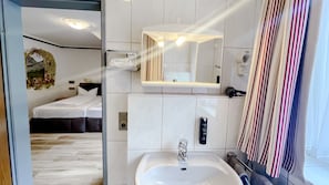A modern bathroom with a sink, mirror, and towel rack. - Comfortable and versatile room -perfect for relaxation, work and exchange (Winterberg)