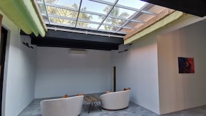 A modern room with a skylight, white walls, and a small table with two white sofas. - Villa Kiprey (Karangasem)
