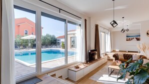 Un salon moderne doté de grandes fenêtres, d’une piscine et d’un coin salon confortable.