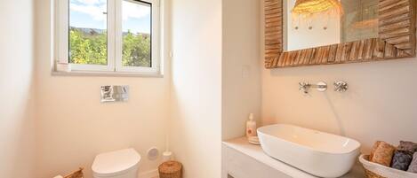 A bathroom with a toilet, bidet, and a large white sink with a mirror above it.