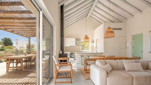 Un vaste espace de vie comprenant un grand canapé, des meubles en bois et une vue sur la terrasse extérieure.