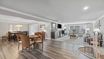 A spacious living area with a dining table, chairs, a sofa, and a staircase.