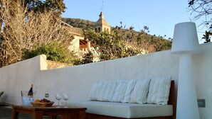 An outdoor seating area with a sofa and a table, a bottle of champagne, and glasses.
