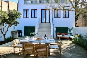 A dining area with a table set for four, outdoor seating, and a staircase leading to a second floor. - Mater Randa,  history peace and Solidarity (Randa)
