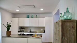 A modern kitchen with white cabinetry, a central island, and a wooden cabinet on the right.