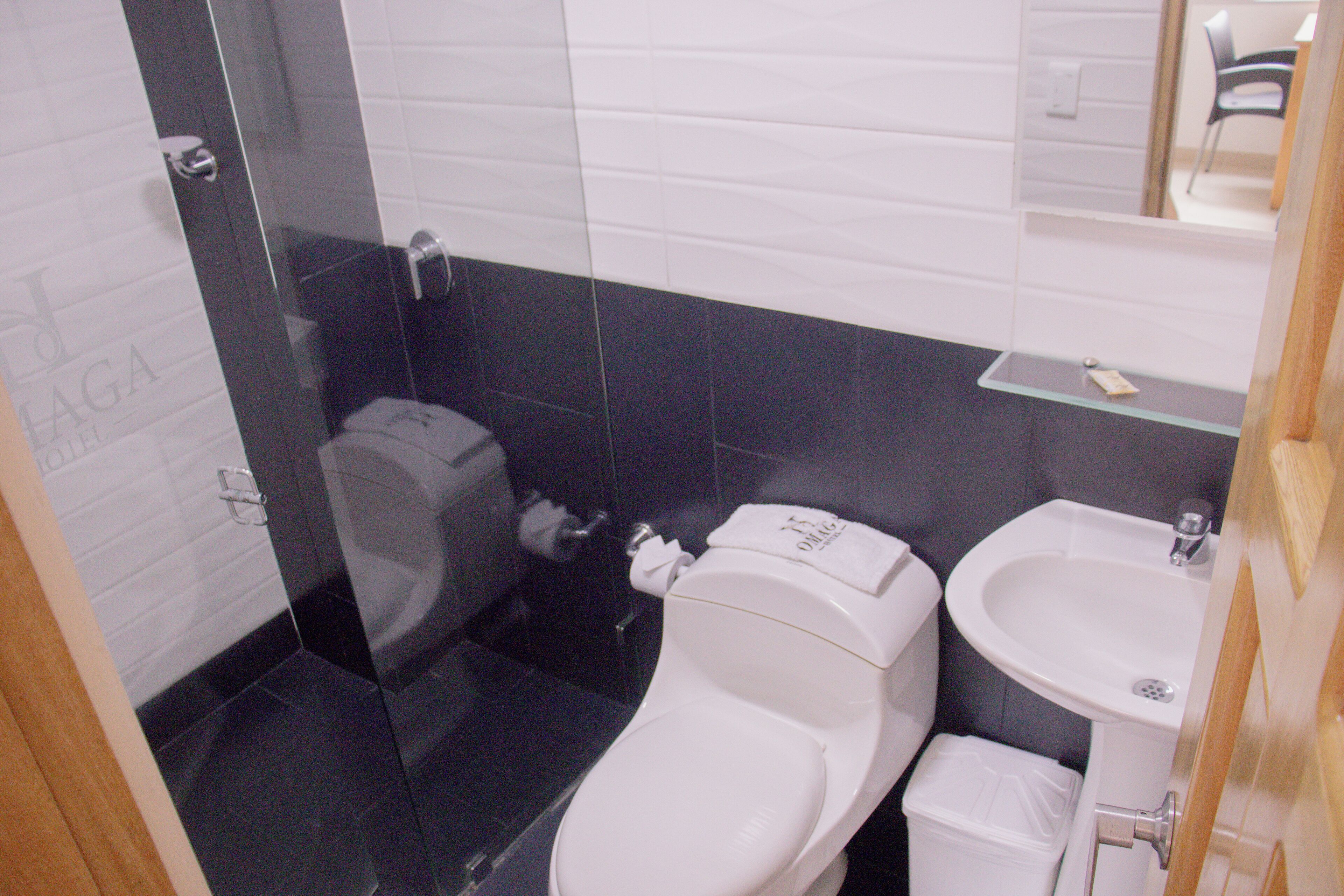 A bathroom with a toilet, sink, and mirror.